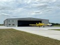 prop plane exiting hangar's large hydraulic door