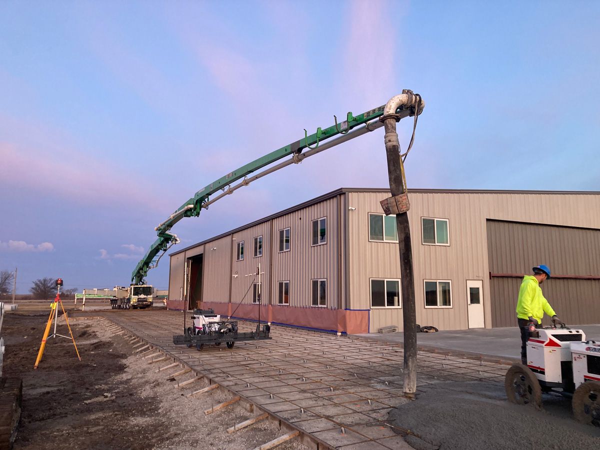 concrete being poured by steel airplane hangar